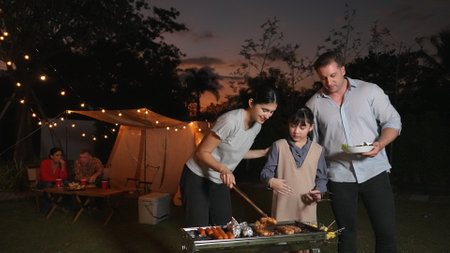 Family celebrate holiday in garden, Mother and child grill food for family member. Outdoor camping activity relax with tasty meal and spend time with young generation cross generation gap. Divergence.の写真素材