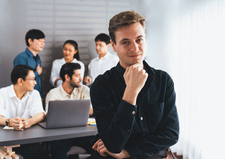 Confidence and happy smiling businessman portrait with background of his colleague and business team working in office. Office worker teamwork and positive workplace concept. Prudentの写真素材