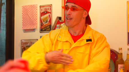 Professional happy hipster looking at his customer drinking milk shake while talking. Emplayee...