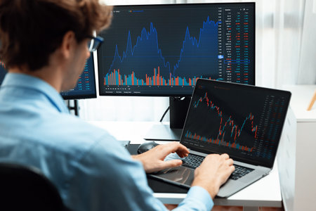 Working young business trader typing, focusing on laptop in market stock graph data investment in...