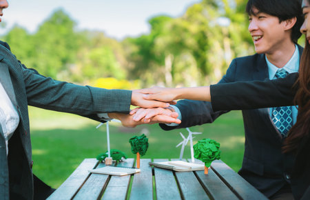 Business people join hand together as teamwork and unity, outdoor business meeting table. Eco-friendly practices and collaboration in corporate social responsibility for greener environment. Gyreの写真素材