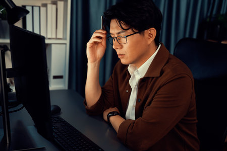Smart businessman in casual day focusing computer to create business plan report over late night time at office, working on searching tools market planning with new startup company project. Infobahn.の写真素材