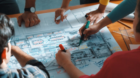 Top view of civil engineer team writing at blueprint at meeting table with color palettes. Group of smart diverse people planning and taking a note while manager looking at project plans. Symposium.の写真素材