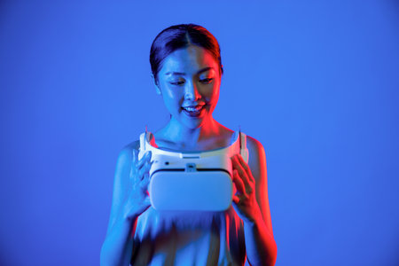 Smart female standing hit by neon light hold VR headset, gadget for connecting metaverse, future...