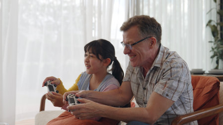 Grandfather and granddaughter together watch interesting entertainment media on TV. Old senior use...