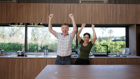 Lovely old marriage couple happily talking about good event or news in kitchen with raise hand pose show enjoyment. Cheerful grandfather and grandmother have happy relationship and family. Divergence.の写真素材