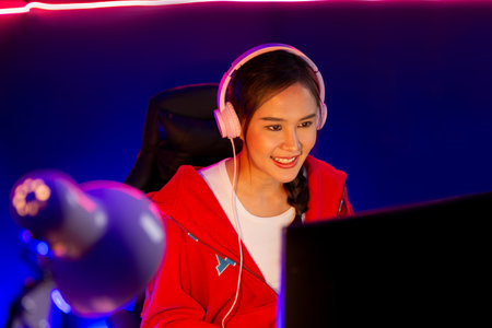 Host channel of smiling beautiful Asian girl streamer playing online game wearing headphone talking...