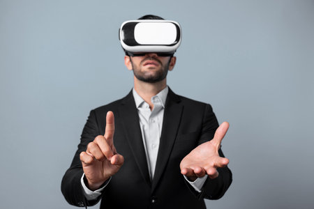 Smart businessman wears VR glasses and standing at white background while holding and pointing at something. Skilled project manager checking data analysis in metaverse or virtual reality. Deviation.の写真素材