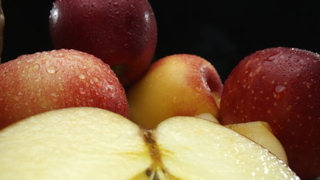 Macrography, slices of fresh apple are arranged on a cutting board against a striking black...