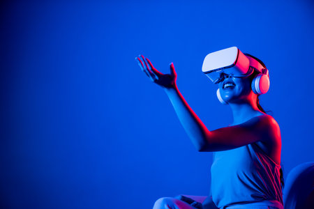 Smart female sitting on sofa surrounded by neon light wear VR headset connect metaverse, futuristic cyberspace community technology, watch and interacting with virtual object with hand. Hallucination.の写真素材