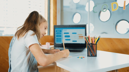Student writing report or doing homework while looking at laptop screen display engineering coding program or programing system. Smart happy girl planing website development in STEM class. Erudition.の写真素材