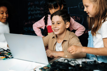 In classroom student in STEM class learning about coding robotics car. Brown shirt Schoolboy and white bib schoolgirl watching laptop and discussing. Other schoolgirls playing around funny. Erudition.の写真素材