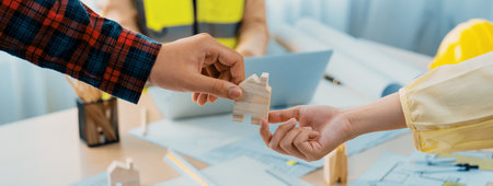 Professional engineer and architect collaborate on eco house project at meeting table with green design blueprint and architectural equipment at modern office. Focus on hand. Close up. Delineation.の写真素材