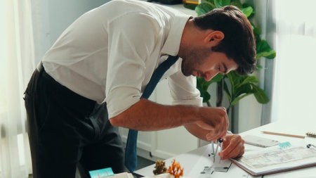 Top down view of smart architect engineer measure blueprint by using architectural equipment while interior designer thinking about building design or house construction at meeting room. Alimentation.の写真素材