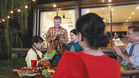 Family together celebrate anniversary in garden. Senior give gift to granddaughter. Outdoor camping activity to relax with relatives, spend time with multigeneration cross generation gap. Divergence.の写真素材
