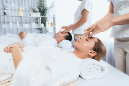 Caucasian couple enjoying relaxing anti-stress head massage and pampering facial beauty skin recreation leisure in dayspa modern light ambient at luxury resort or hotel spa salon. Quiescentの写真素材