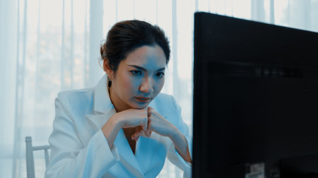 Diligent and serious working young businesswoman sitting on the workspace desk using laptop computer for internet online content writing or secretary remote working from home. Vivancyの写真素材