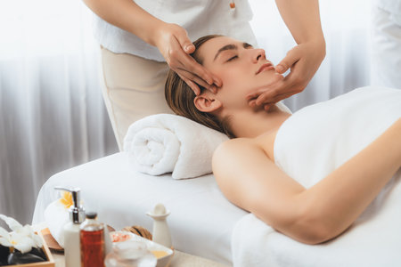 Caucasian woman enjoying relaxing anti-stress head massage and pampering facial beauty skin recreation leisure in dayspa modern light ambient at luxury resort or hotel spa salon. Quiescentの写真素材