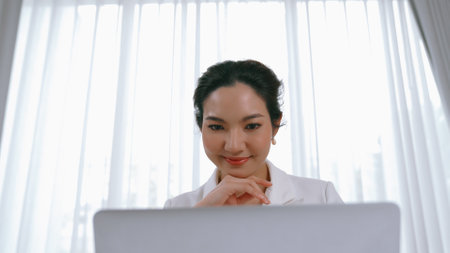Young businesswoman sitting on the workspace desk using laptop computer for internet online content writing or secretary remote working from home. Vivancyの写真素材