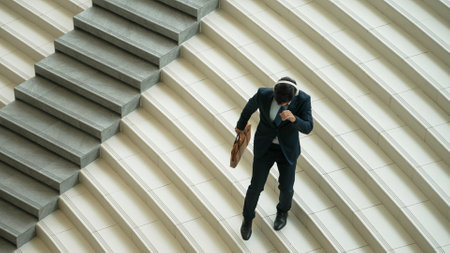 Happy business man listening to music from headphone while walking down at stairs. Executive manager dancing to celebrate increasing sales or successful project or getting new position. Exultant.の写真素材