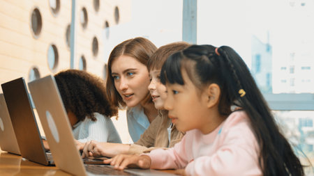 Smart teacher teaching and looking student using laptop at classroom. Professional instructor...