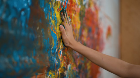 Side view of highschool girl hand placed at colorful stained wall and remove the hand. Closeup of room was pained or decorated with hand print in art lesson. Creative activity concept. Edification.の写真素材