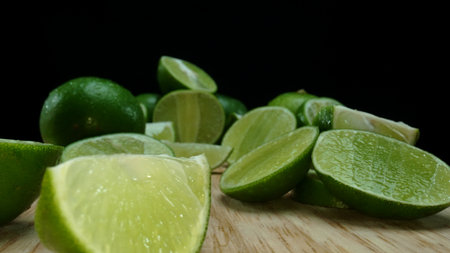 Close-up, a vibrant slice of fresh lime rests upon a rustic wooden cutting board, exuding freshness...
