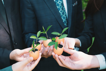 Group of business people holding repuposed eggshell transformed into fertilizer pot, symbolizing...