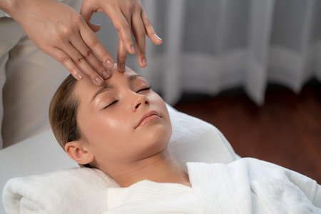 Caucasian woman enjoying relaxing anti-stress head massage and pampering facial beauty skin recreation leisure in dayspa modern light ambient at luxury resort or hotel spa salon. Quiescentの写真素材