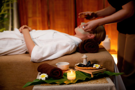 Serene ambiance of spa salon, woman customer indulges in rejuvenating with luxurious face cream massage with warm lighting candle. Facial skin treatment and beauty care concept. Quiescentの写真素材