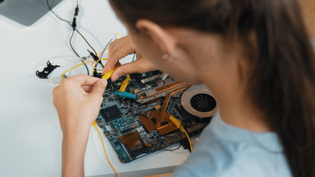 Top view of young highschool girl fixing mainboard at STEM technology class. Closeup of caucasian...