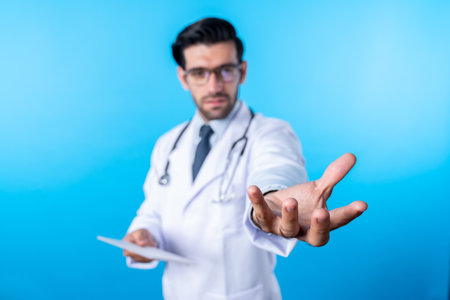 Close up of skilled doctor holding something his hands while standing at blue background....