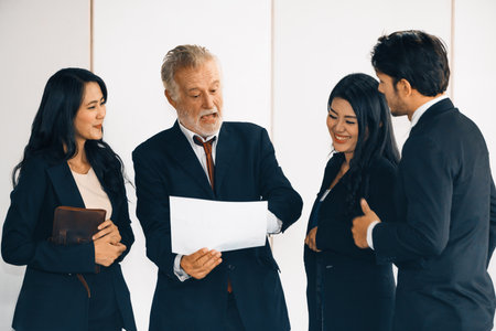Senior caucasian manager working in office with assistance of young Asian business people and...