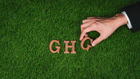 Hand arrange wooden alphabet text in GHG on biophilic green grass background as eco symbol for encouraging message for greenhouse gases emission reduction campaign and environmental awareness. Gyreの写真素材