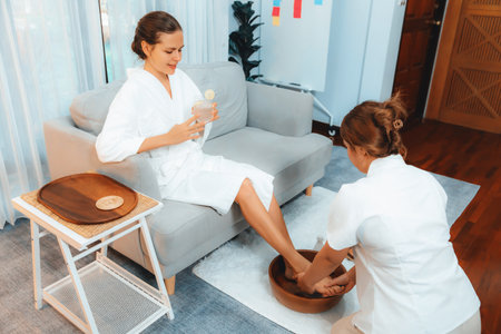 Woman indulges in blissful foot massage at luxurious spa salon while masseur give reflexology therapy in gentle day light ambiance resort or hotel foot spa. Quiescentの写真素材