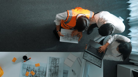 Top down view of project manager and civil engineer hold laptop while explain idea to architect....