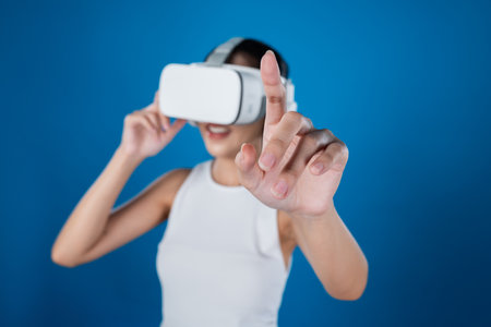 Smart female standing with blue background wearing VR headset connecting metaverse, futuristic...