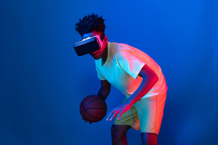 Young African American basketball gaming player wearing VR bouncing pose on blue pink neon light connecting digital futuristic technology virtual reality at metaverse world playing court. Contrivance.の写真素材