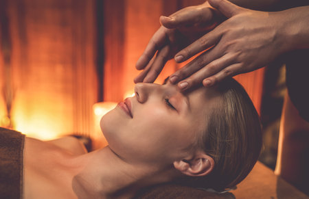Closeup caucasian woman enjoying relaxing anti-stress head massage and pampering facial beauty skin recreation leisure in warm candle lighting ambient salon spa in luxury resort or hotel. Quiescentの写真素材