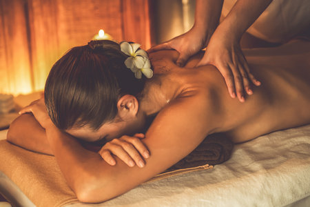 Caucasian woman customer enjoying relaxing anti-stress spa massage and pampering with beauty skin recreation leisure in warm candle lighting ambient salon spa at luxury resort or hotel. Quiescentの写真素材