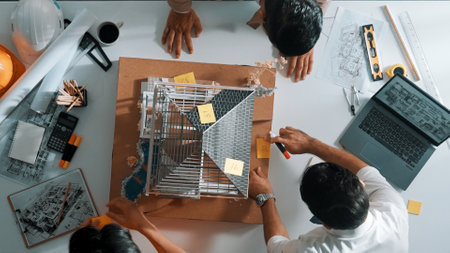 Close up of civil engineer hand holding blueprint while working together to plan building construction by using house model and shaking hand or making a deal or contract with manager. Alimentation.の写真素材