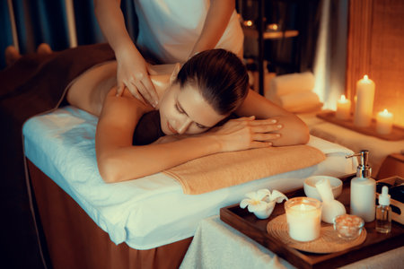 Caucasian woman customer enjoying relaxing anti-stress spa massage and pampering with beauty skin recreation leisure in warm candle lighting ambient salon spa at luxury resort or hotel. Quiescentの写真素材