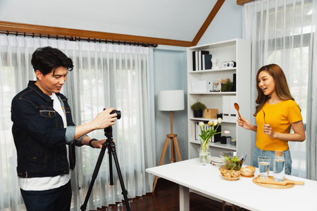 Asian beautiful woman food specialist presenting healthy meal wholegrain bun bread basket on live channel recorded video camera by smart cameraman streaming lifestyle social media online. Infobahn.の写真素材