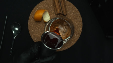 Close up of bartender hand pouring Tequila sunrise cocktail with lemon. Macro of bartender skilled hand preparing for serving cocktail and garnished with citrus. Top down aerial view. Comestible.の写真素材