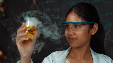 Closeup of smart highschool student inspect colored solution at blackboard. Beautiful scientist...