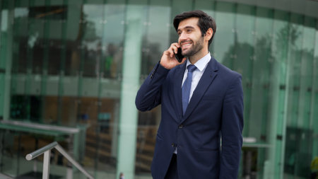 Skilled caucasian project manager calling phone while walking at city with blurred background. Skilled businessman using smart phone talking to project manager with blurred background. Exultant.の写真素材