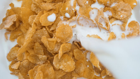 Close up of a white bowl of cereal with milk being poured into it. Macrography of white milk pouring...