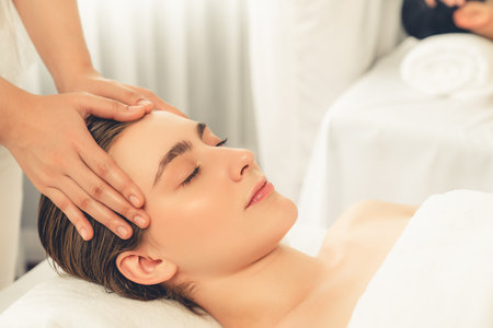 Caucasian couple enjoying relaxing anti-stress head massage and pampering facial beauty skin recreation leisure in dayspa modern light ambient at luxury resort or hotel spa salon. Quiescentの写真素材