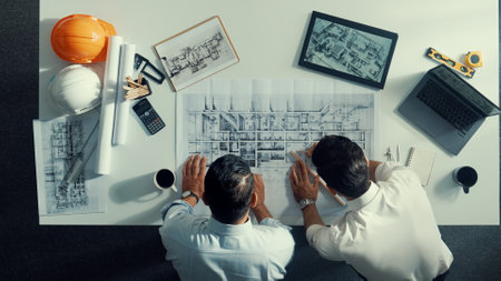 Top view of skilled civil engineer working together to plan building design. Top down aerial view of skilled architect team sitting at table while manager using tablet open project plan. Alimentation.の写真素材