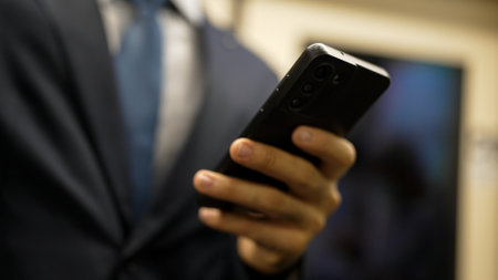 Closeup of business man hands looking phone while standing at train surrounded by people. Caucasian project manager checking email, planing marketing strategy with blurred background. Exultant.の写真素材